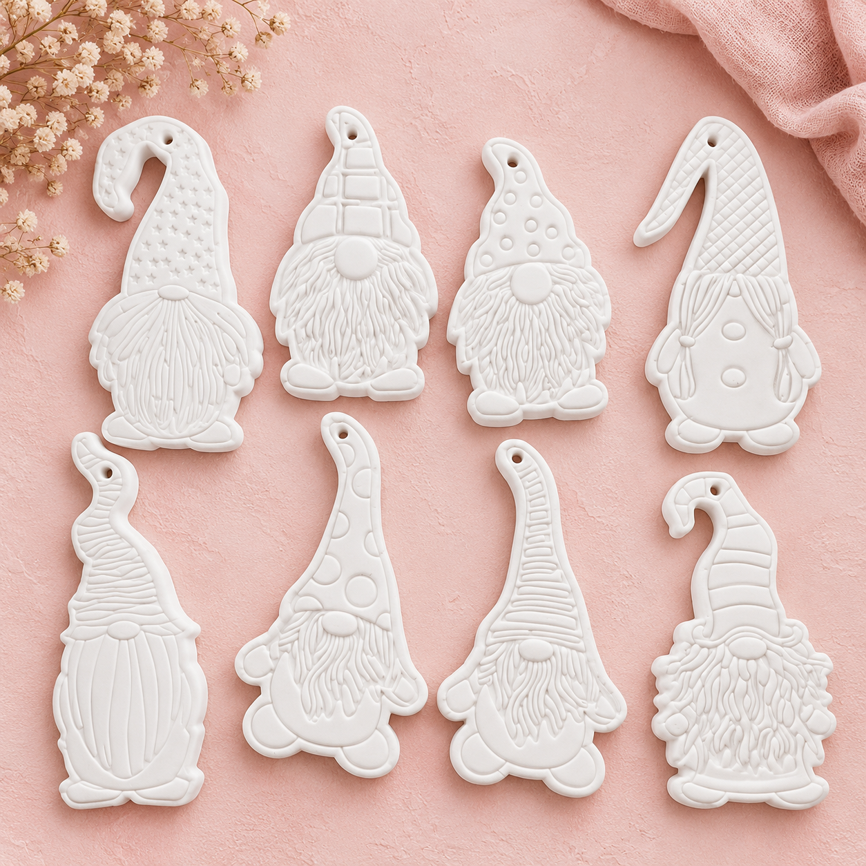 Witte gnome-hangers met patroonmutsen en structuur op een pastelroze achtergrond.