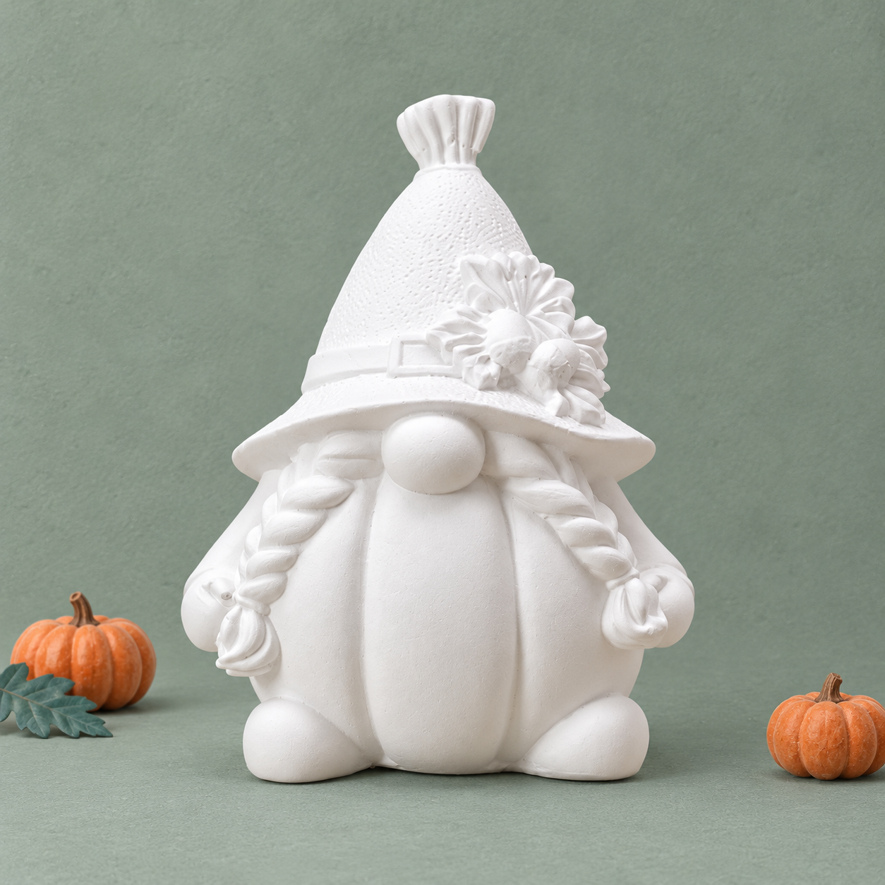 Wit gnomebeeldje met pompoenbuik, vlechten en bloemen op de hoed